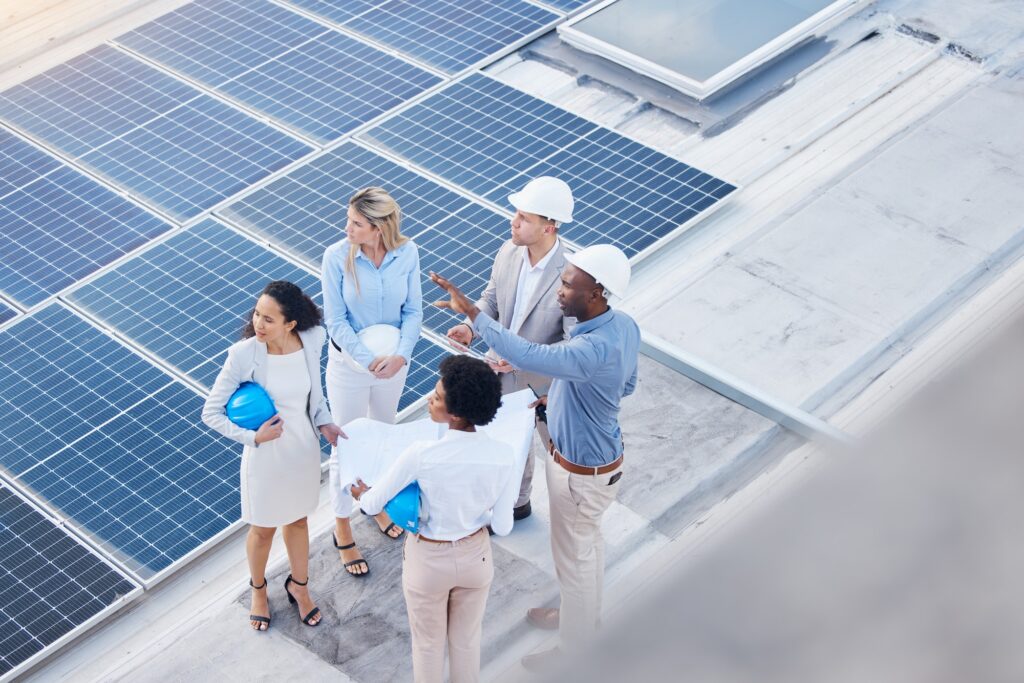 Solar energy, teamwork or engineering team on roof by solar panels for electricity technology innov